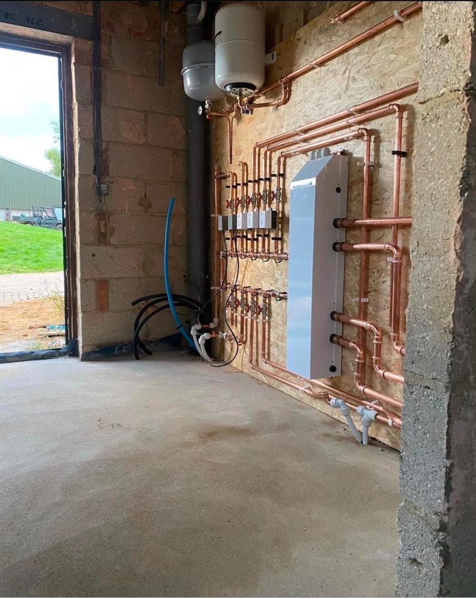 Heat pump plant room first fix with copper pipework set square around a hydraulic separation unit and expansion vessels