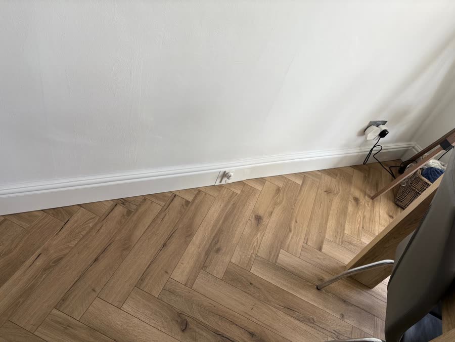 ThermaSkirt along a white wall over pale herringbone flooring
