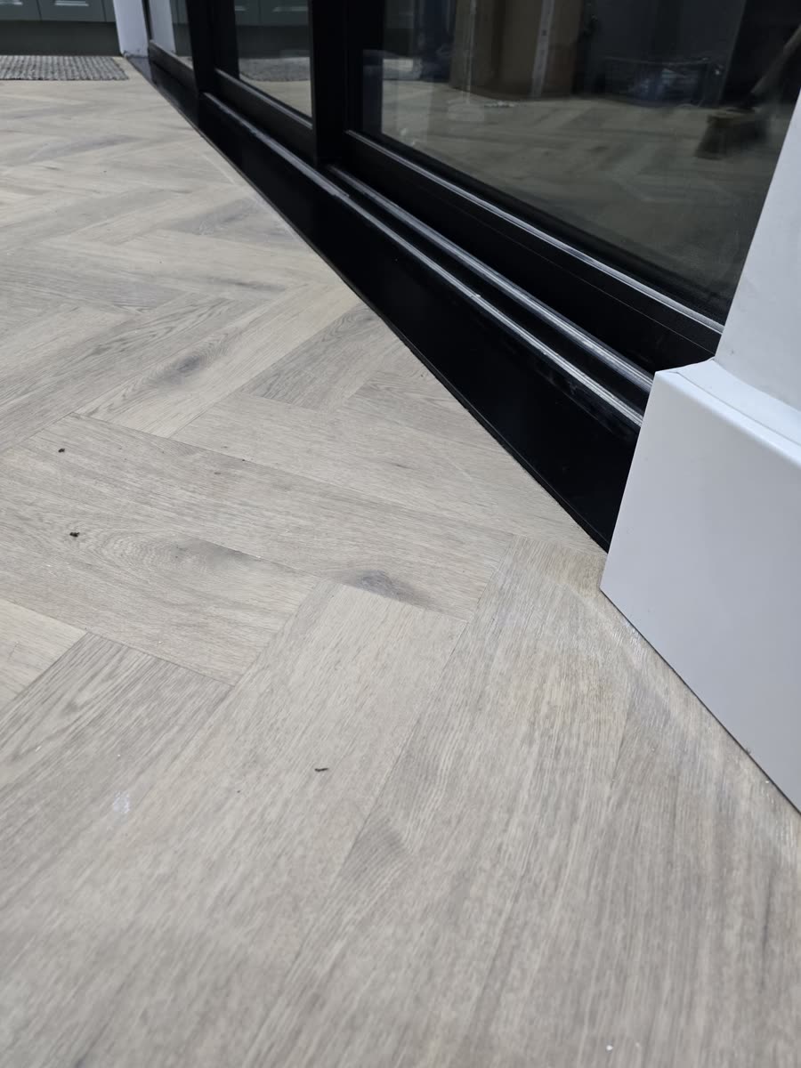ThermaSkirt running to an aluminium sliding door on pale herringbone